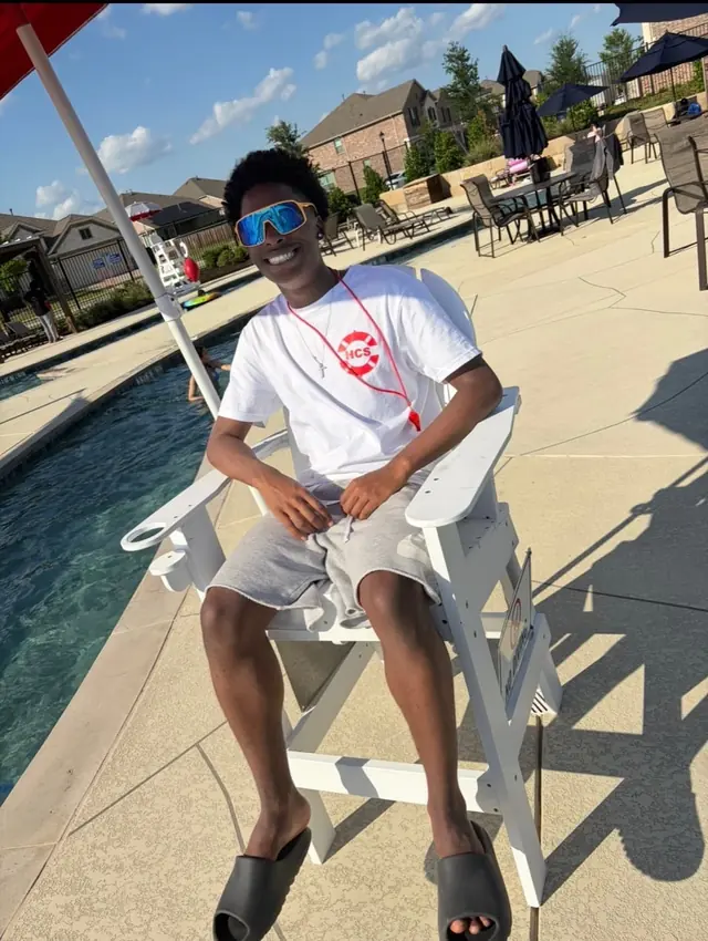 A pool monitor on duty at the edge of a community pool.